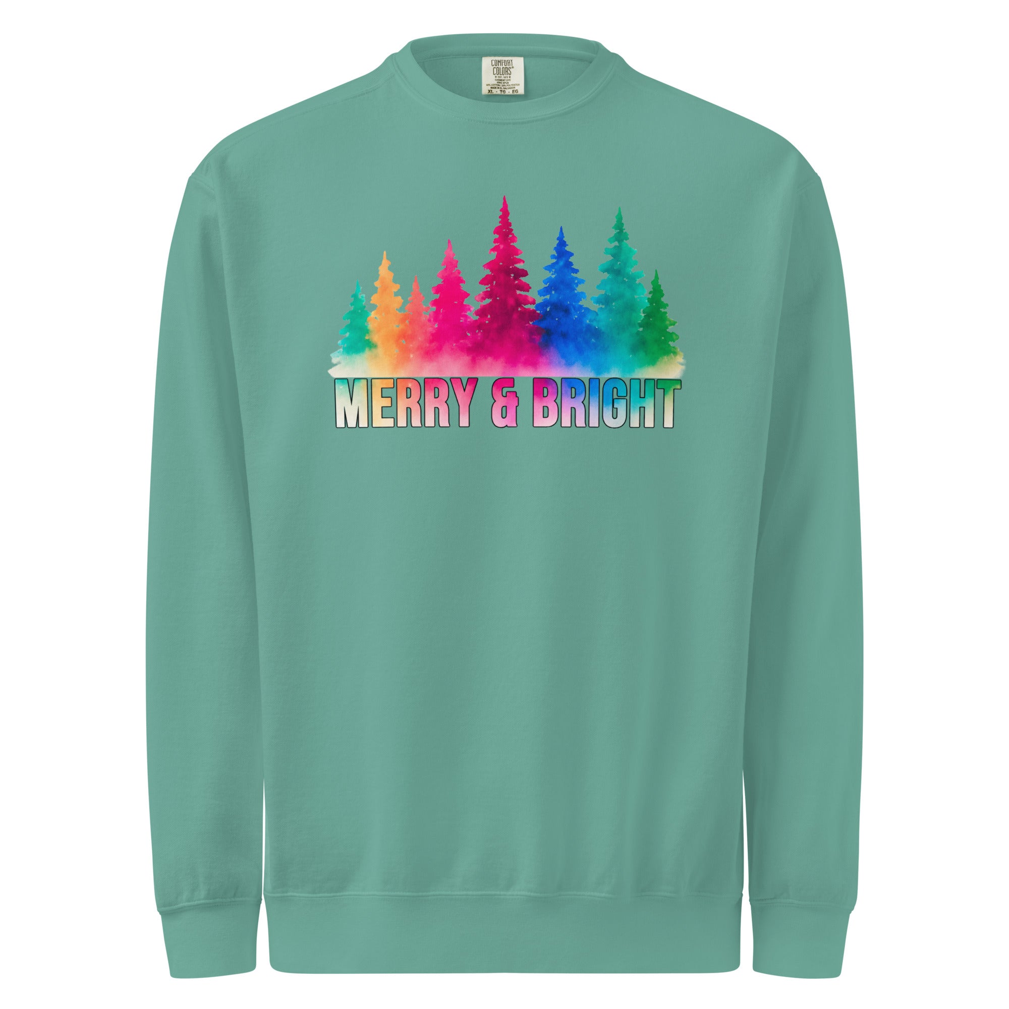 A green sweatshirt with a colorful graphic design featuring a line of trees with different colored leaves, and the text "MERRY & BRIGHT" printed below.